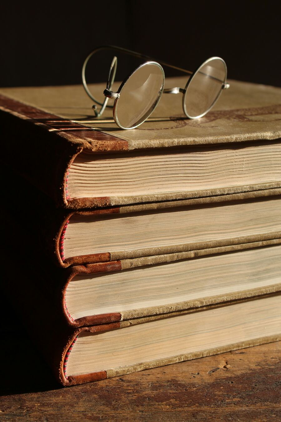 Gestapelte antike Bücher mit alter Lesebrille